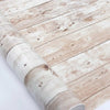 Close-up of a roll of retro wood grain self-adhesive wallpaper on a wooden surface.