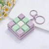 A square box of pastel colored tactile clicking keyboard fidget toys with a purple keychain attached on a white surface.