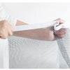 A hand is holding a white reusable self-adhesive mosquito window screen fabric over an arm.