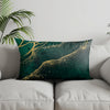 A decorative pillow featuring a dark teal background with gold leaf accents depicting a landscape.