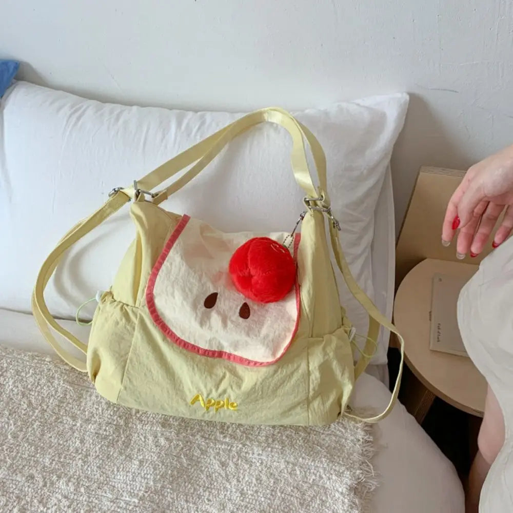 A light yellow nylon messenger bag shaped like a face with a red nose and ears, resting on a white pillow.