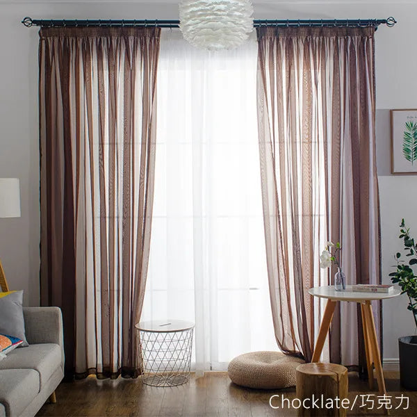 Brown sheer voile curtains with a rod pocket filtering light through a window.