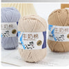 A close-up of a skein of light beige milk cotton blend yarn with a label showing the product name and usage instructions.