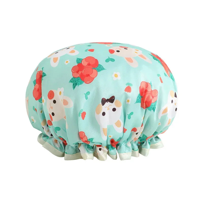 A light mint green reusable waterproof shower cap featuring a pattern of cartoon animals and red flowers.
