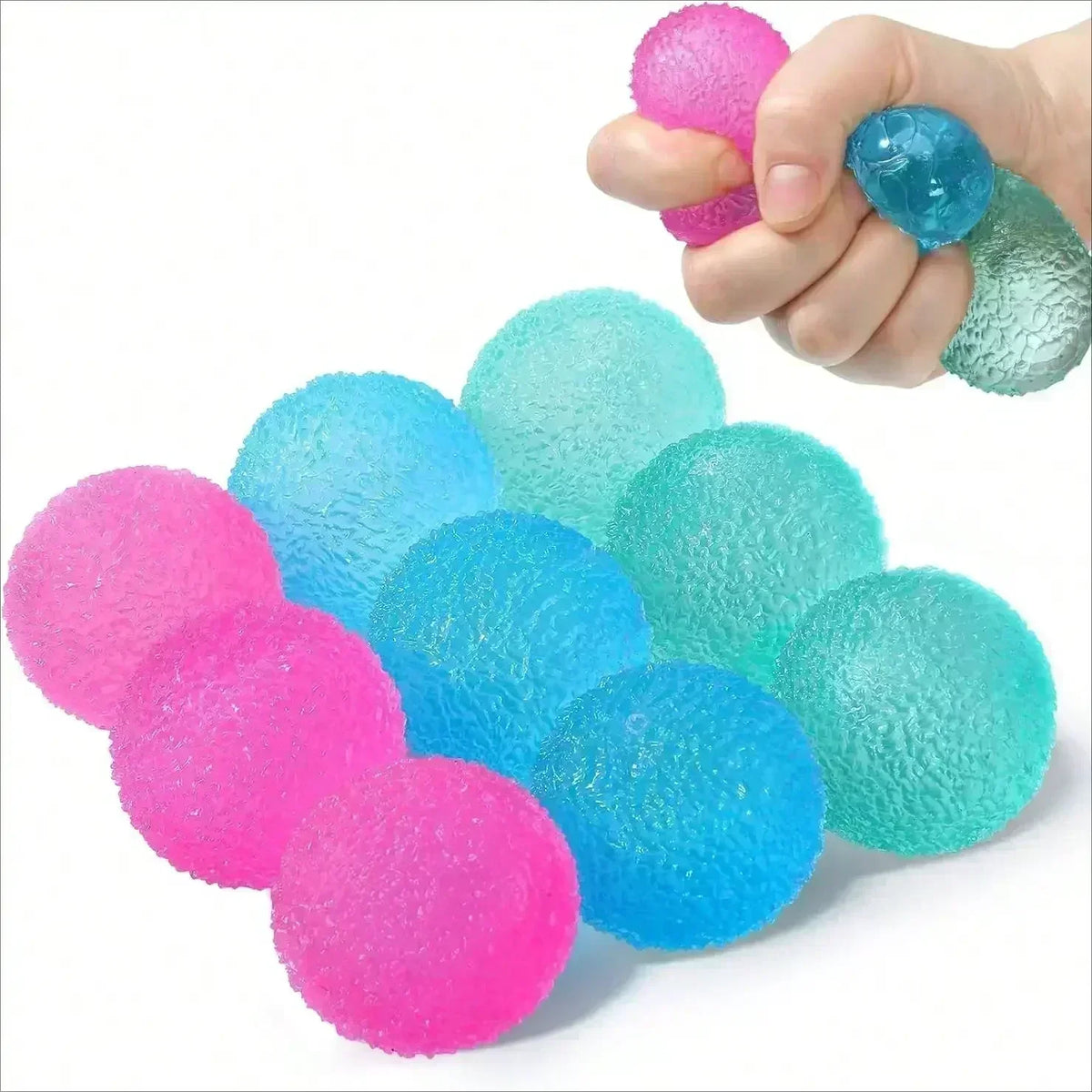 A hand is squeezing a bright pink textured stress ball, with several other colored balls scattered nearby.