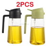 A pair of clear glass oil spray bottles with black and light green tops for cooking.