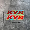 Red and green KYB motocross motorcycle fork stickers displayed against a gray textured background.