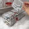 A hand is holding a clear jewelry organizer box with multiple compartments filled with various beads and jewelry.
