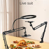 A black adjustable phone stand with an overhead light is set up on a wooden table for live streaming or recording.