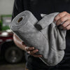 A hand holds a roll of gray microfiber cleaning cloths.