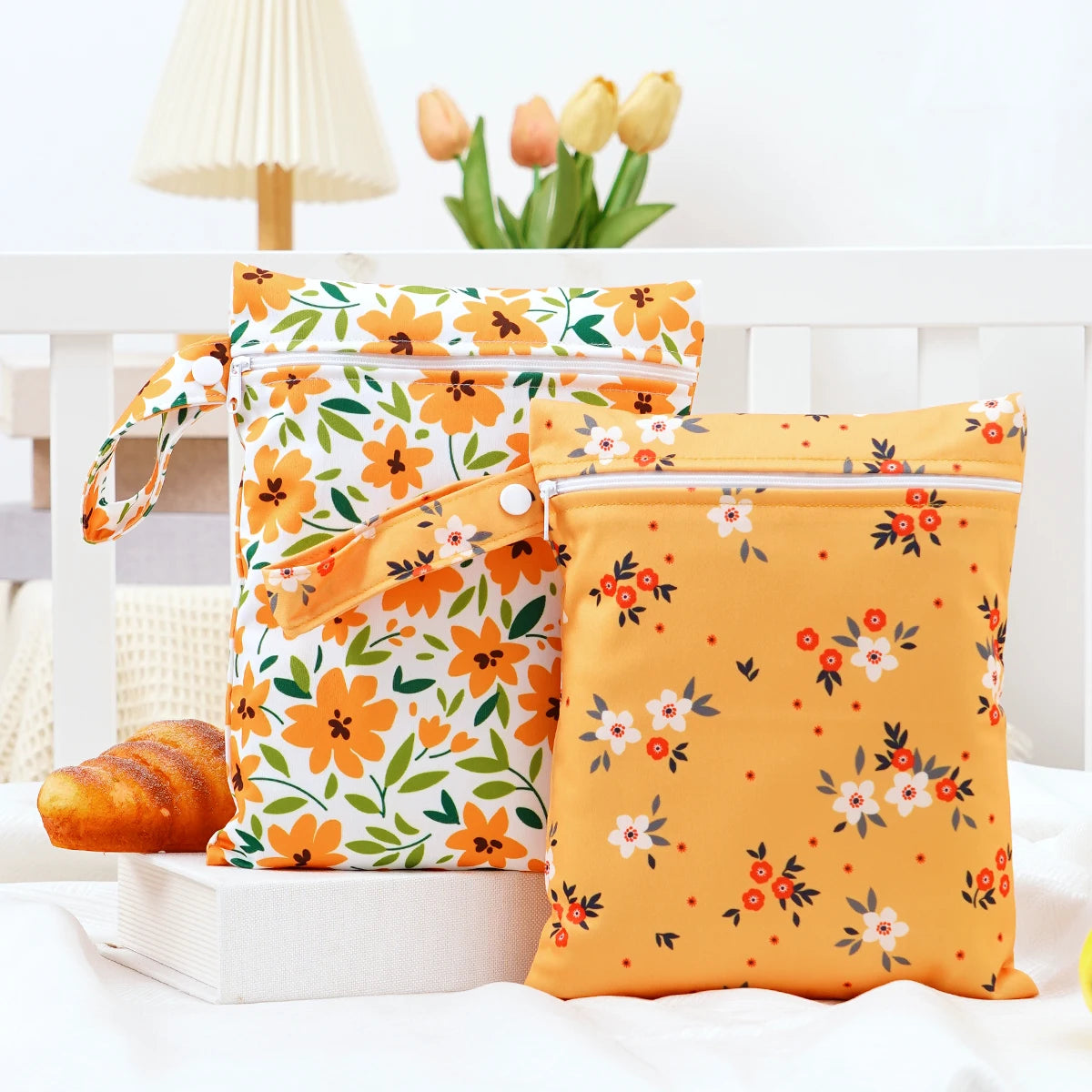 A pair of bright orange and white floral mini waterproof wet dry bags for baby are displayed on a white surface.