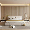 A modern bedroom featuring a white upholstered bed against a vertical wood slat wall with recessed lighting.