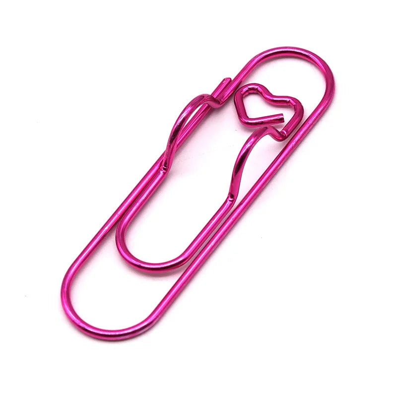 منظم مكتب معدني وردي يحمل قلماً على شكل قلب.