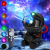 A black astronaut night light projector with a red strap and a remote control, displaying colorful galaxy lights.