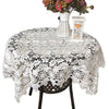 White lace tablecloth with embroidered rose design set on a table.