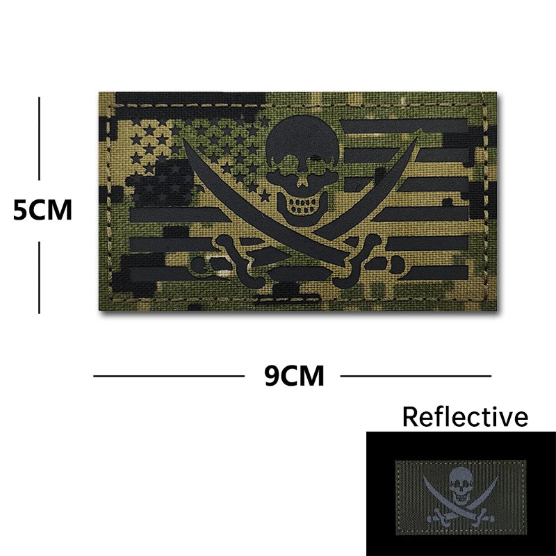 A dark olive green embroidered patch featuring a skull and crossbones design with reflective accents.