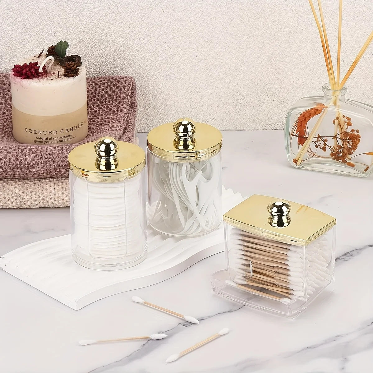 Elegant apothecary jar with a golden lid for cotton balls and swabs, displayed on a marble surface.