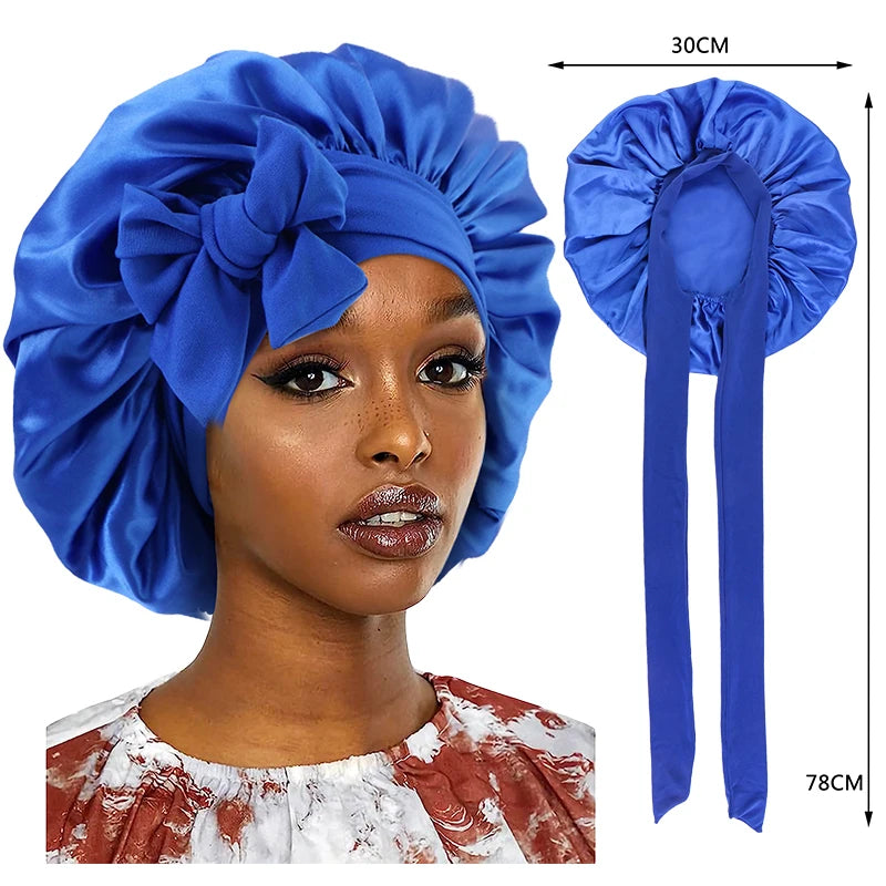 A woman wearing a blue silky satin sleep cap with a wide band and long ties.