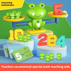 A green frog toy is balanced on a beam, demonstrating math concepts like addition and subtraction.