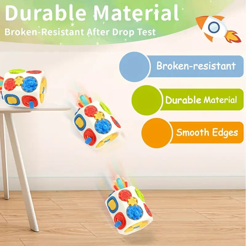 A colorful Montessori busy cube toy with smooth edges is shown falling onto a wooden floor.