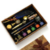 A wooden box contains a vintage calligraphy fountain pen set with various tools and a wax seal stamp kit.