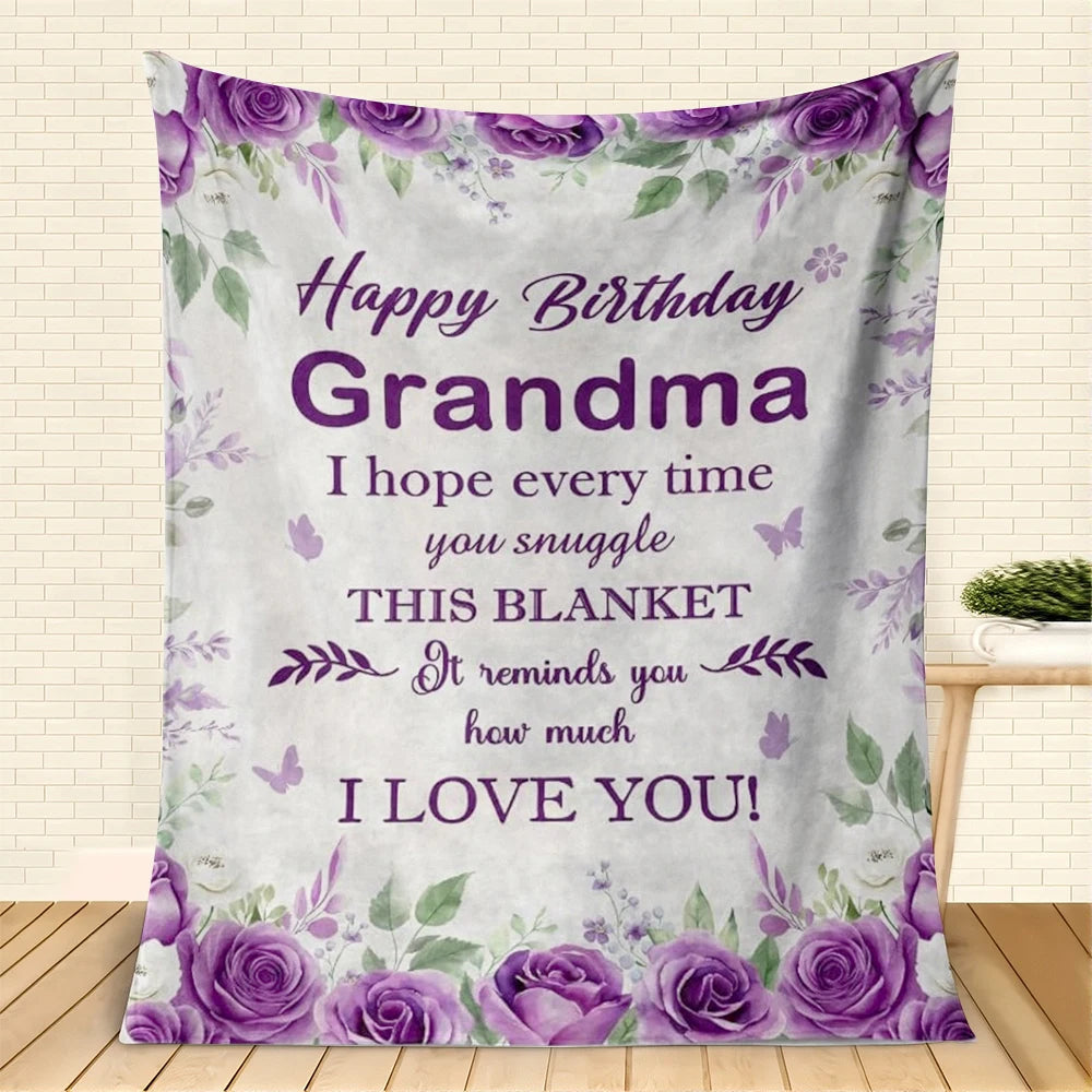 Lila Blumendecke mit 'Alles Gute zur Geburt Oma' und Rosen als Geschenk.