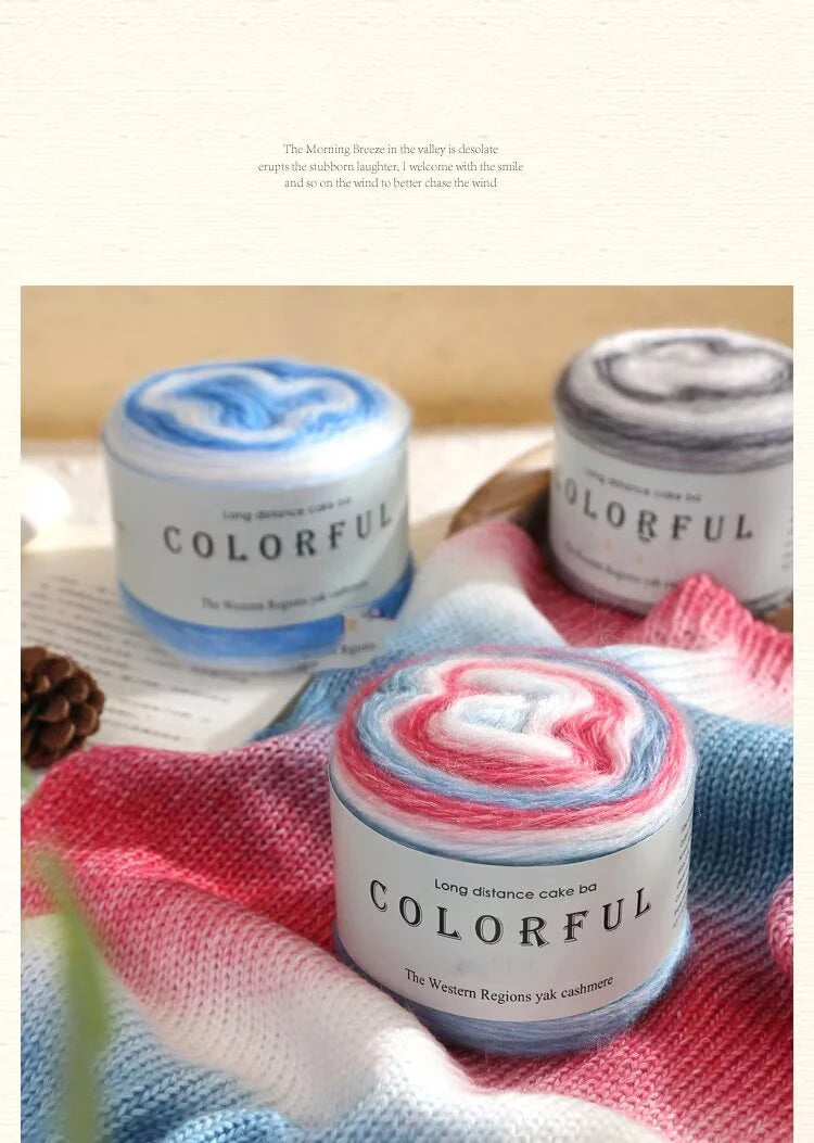 A close-up of Colorful Long distance cake yarn in various shades resting on a pink and blue knitted fabric.