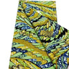 Close-up of pink glitter African wax print fabric featuring green and yellow leaf patterns.