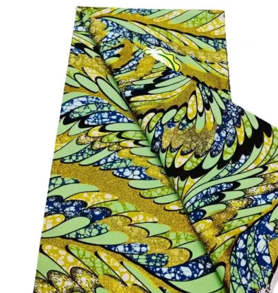 Close-up of pink glitter African wax print fabric featuring green and yellow leaf patterns.