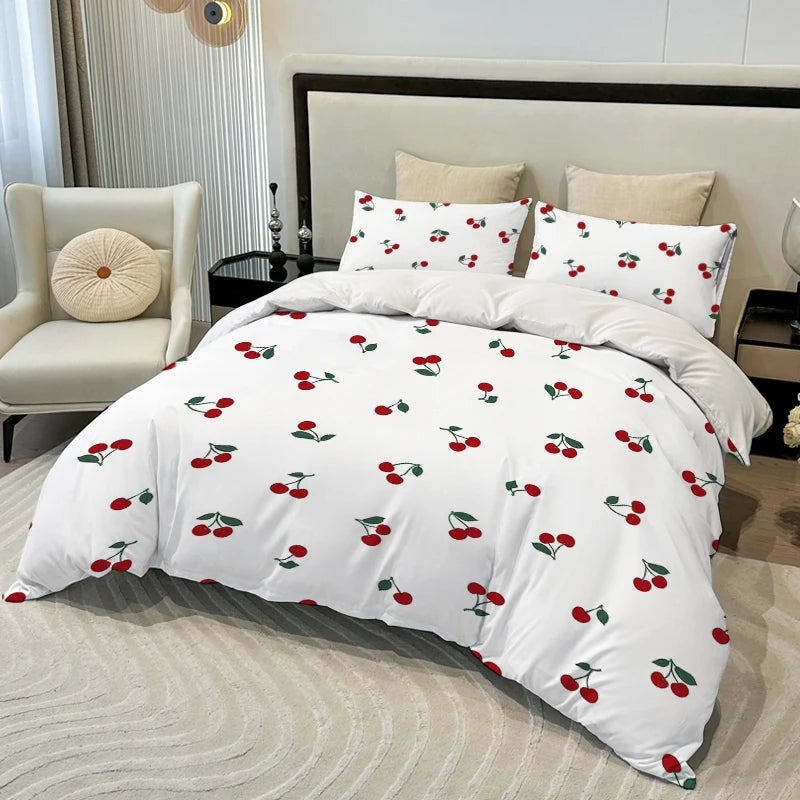 White duvet cover set with a red cherry print featuring various cherry designs and pillows on a bed.