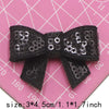 Black and silver sequin bow patches for DIY crafts displayed on a pink grid background.