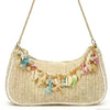 A beige straw shoulder bag adorned with colorful ocean shell charms and a gold chain.