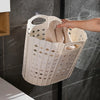 A white folding laundry basket with handles is shown hanging on a glass shower door, holding a towel.