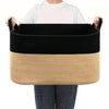A black and beige woven cotton rope storage basket being held by a person.