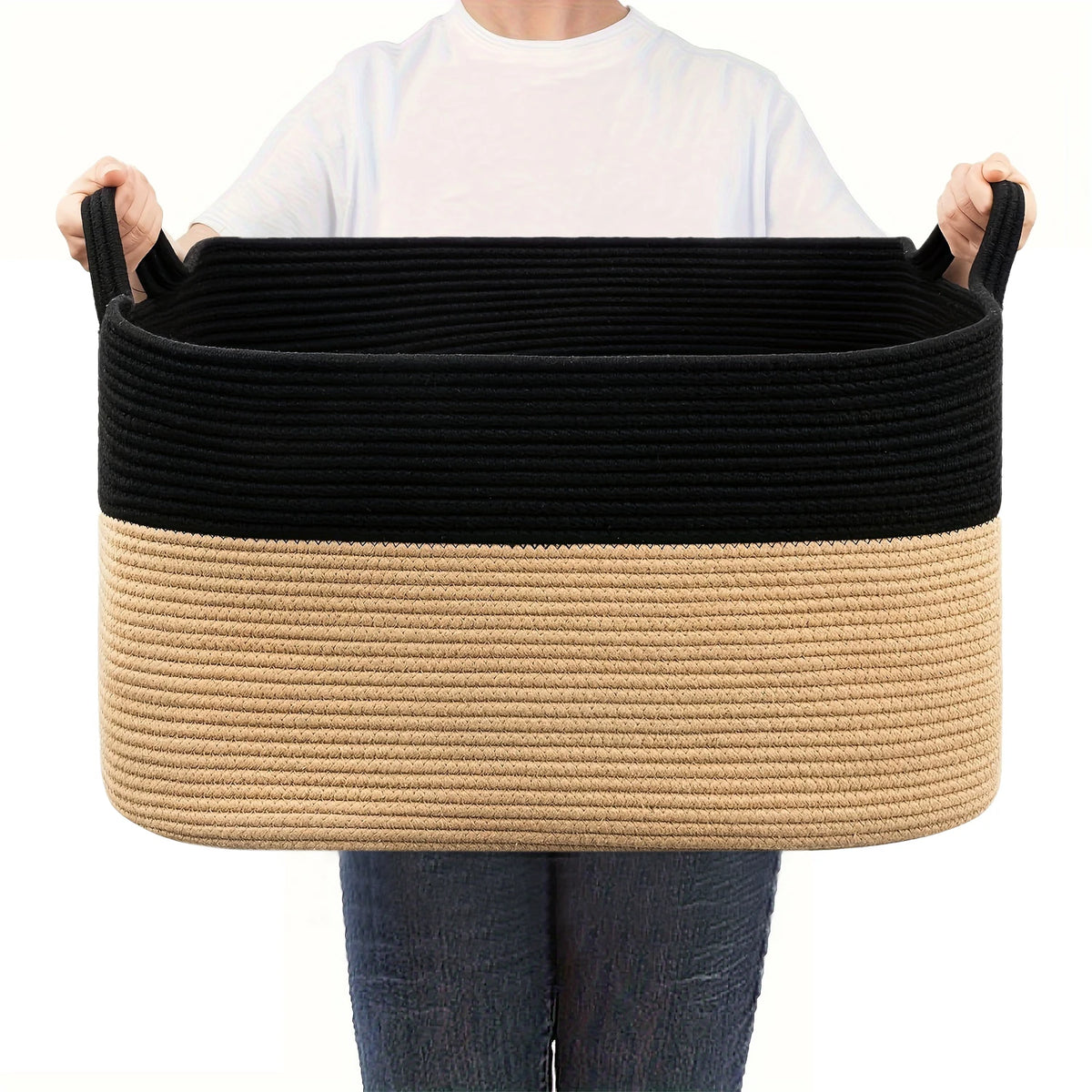 A black and beige woven cotton rope storage basket being held by a person.