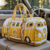 Yellow quilted travel duffle bag with sunflower and peace sign embroidery resting on a light-colored car seat.