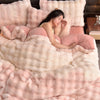 A woman is relaxing on a pink faux fur bedding set with matching pillows and a duvet.