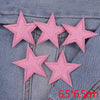 A set of five pink glitter star iron-on embroidered patches placed on a denim fabric.
