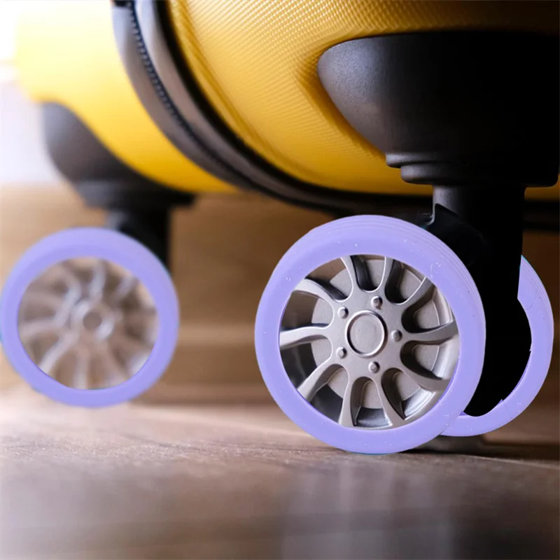 A close-up view of four purple silicone wheel protectors on a yellow suitcase caster wheel.