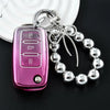 A pink soft TPU car key cover with a metal keyring and chain attached to a silver charm bracelet.