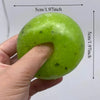 A hand holds a bright green, squishy fidget ball with a hole in the center.