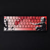 Gros plan sur un clavier mécanique avec des touches personnalisées Raven Sakura rouges et blanches.