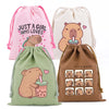 Three drawstring storage bags featuring cute capybara illustrations in pink, cream, and olive green.