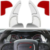 A pair of silver shift paddle extenders shown alongside a car's interior dashboard.