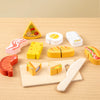 A wooden pretend play set featuring various fruit and vegetable shapes, including a pyramid, slices, and cutting tools.