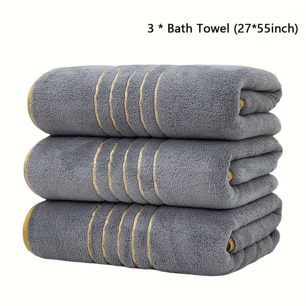 Three gray bath towels with gold accents stacked neatly.
