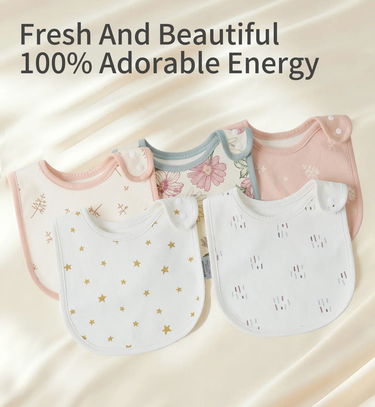 A collection of pink and white cotton baby bibs with floral and star patterns displayed on a light background.