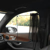 A black sunshade is installed in a car window using suction cups, visible inside the vehicle.