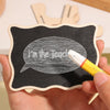 A hand holds a mini wooden chalkboard sign with a speech bubble drawn on it using white chalk.