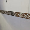 A decorative brown acrylic mirror border with an intricate geometric pattern mounted on a white wall.